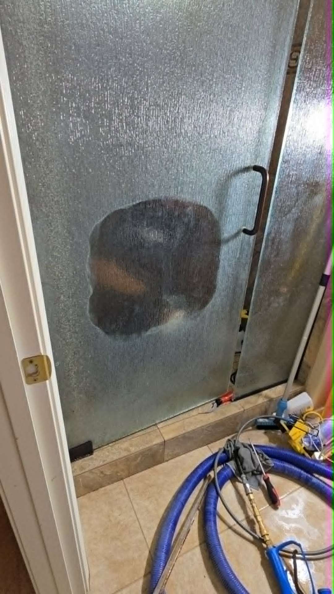 Hand wiping a hard water etched frameless shower glass door in a Gilbert Arizona master bathroom showing dramatic clarity restoration after Lazona Tile Care professional shower restoration