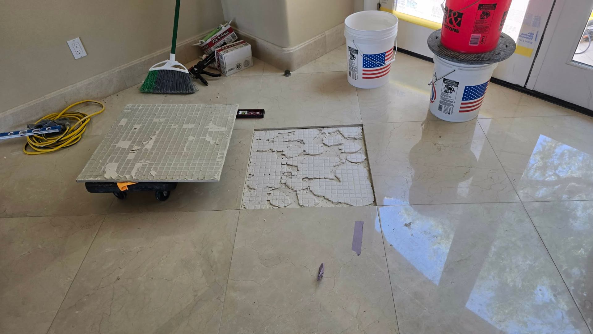 Underside of a failed marble tile pulled from a Paradise Valley floor showing only spot bonded mortar dabs in the four corners with bare unbonded center revealing the production installer skipped back buttering and full mortar coverage that caused hollow tile and cracking