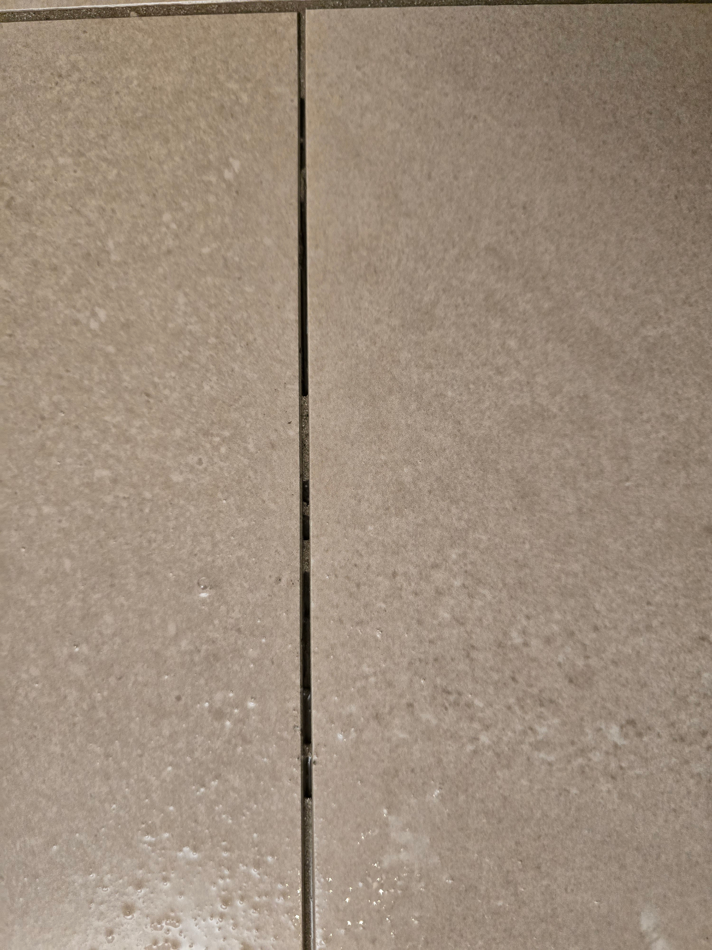 Vertical shower wall grout joint in a new East Valley Arizona home crumbling and sandy from improperly neutralized acidic haze remover and over-watered grout mix during installation